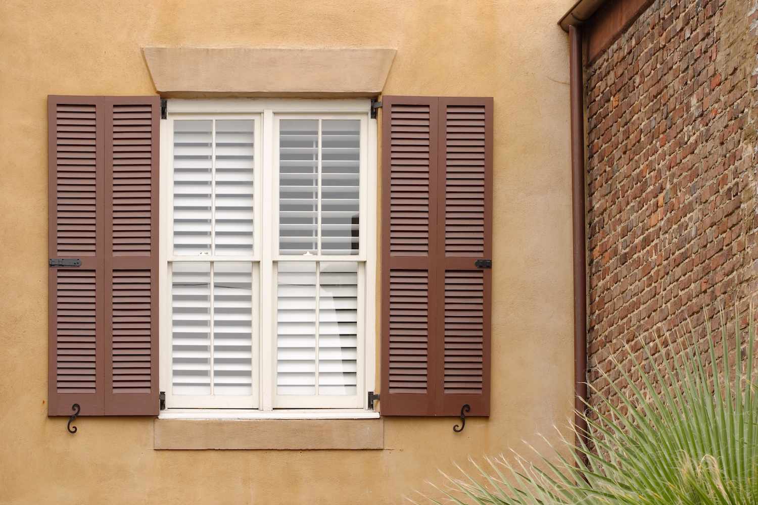 Hellbraunes Haus mit ziegelroten Fensterläden