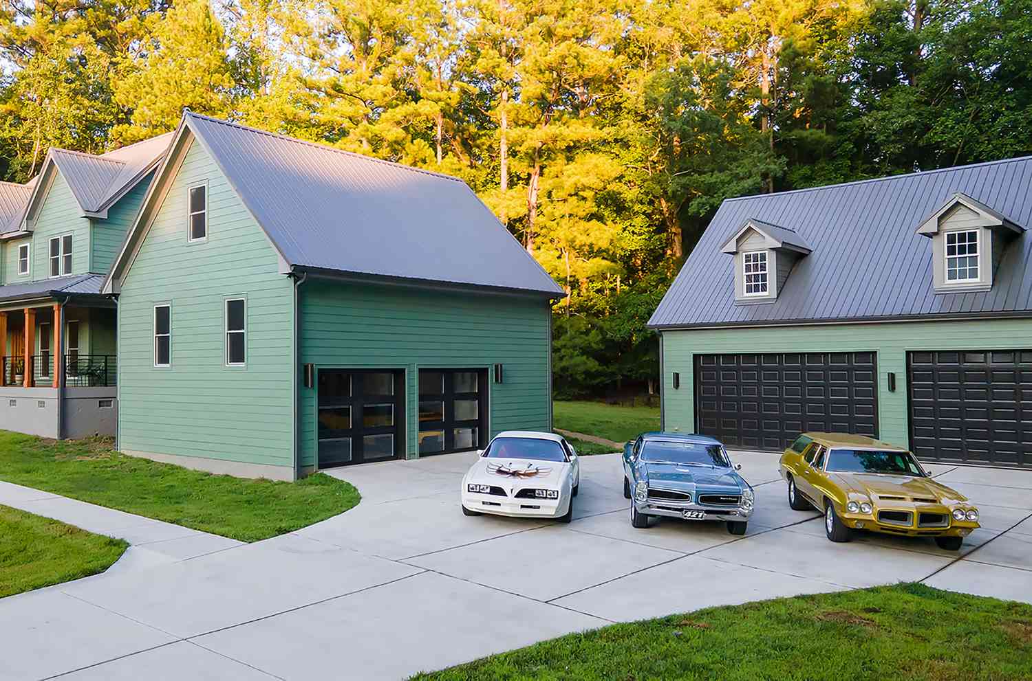 Grünes Haus mit freistehender Garage mit Fenstertüren.