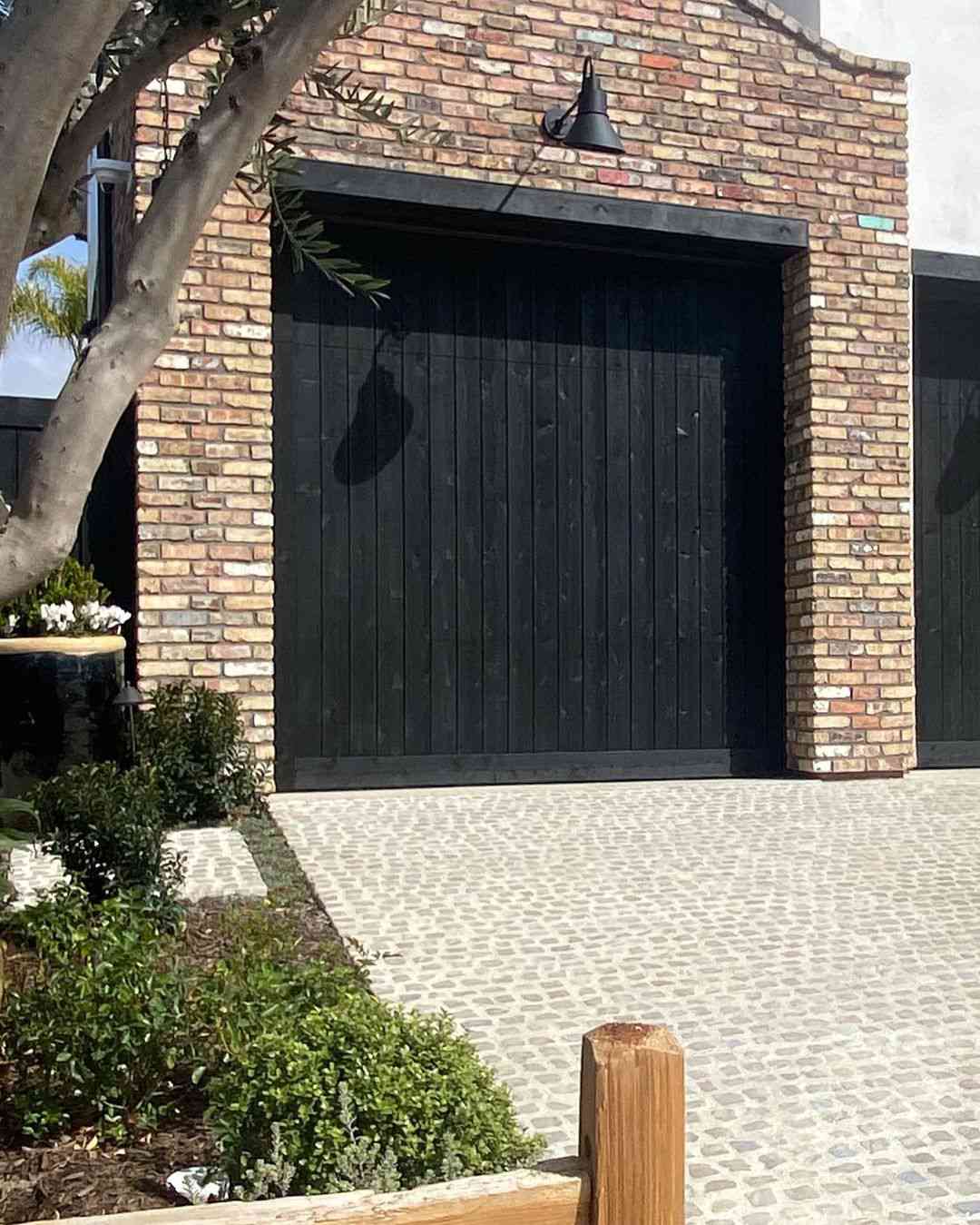 Hohe schwarze Garagentore aus Holz mit Lamellen.