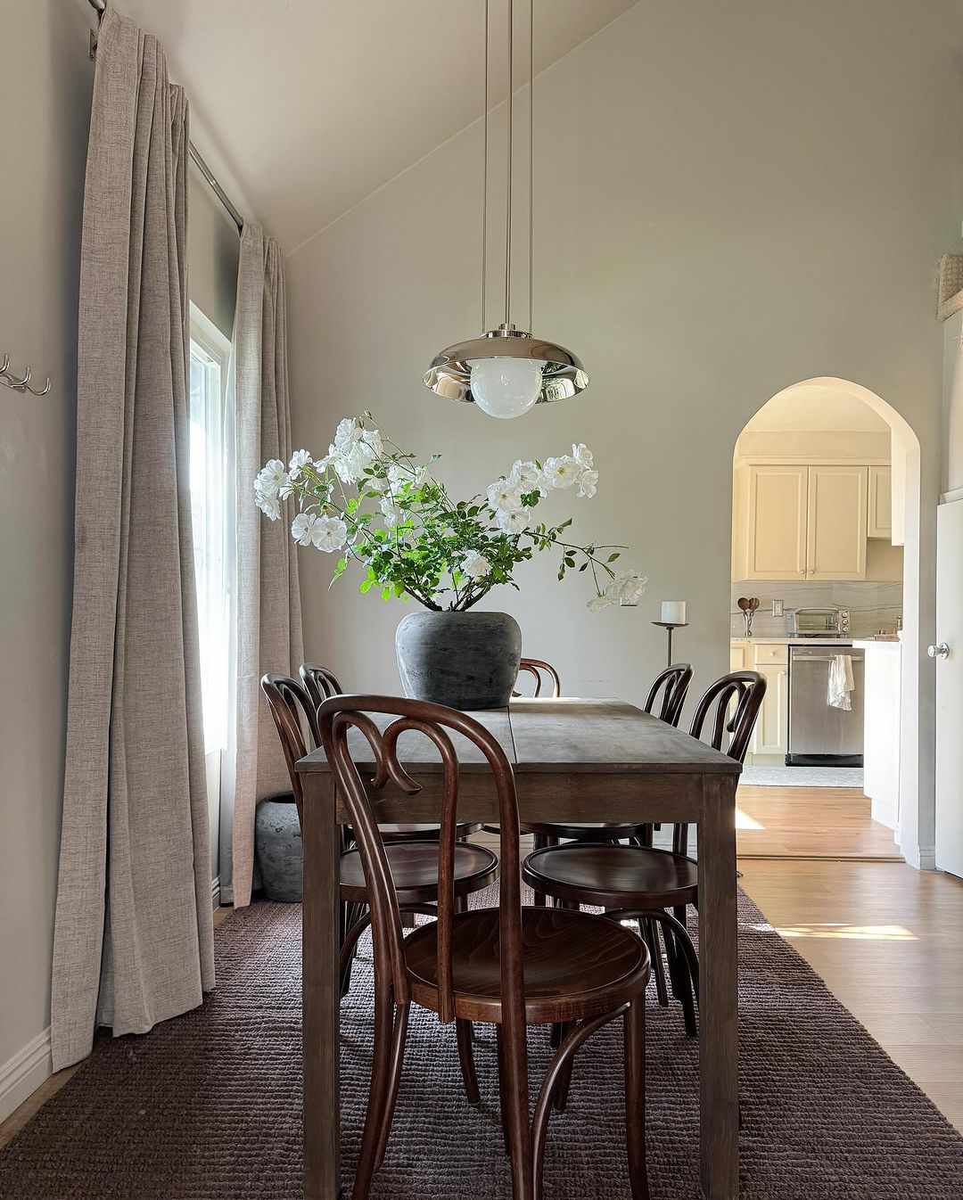 Esszimmer mit rostigem Bauernhoftisch, industrieller Chrom-Hängeleuchte und Bugholzstühlen im Thonet-Stil