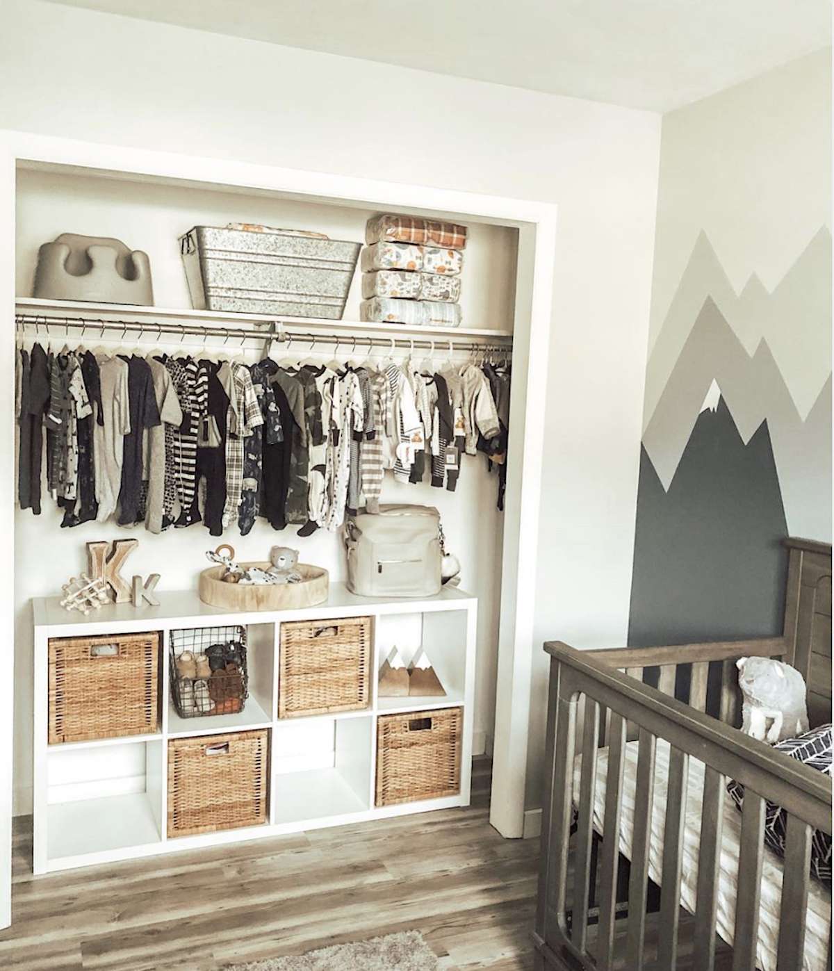 nursery with closet that has no doors, shelving storage on top and storage unit with wicker baskets below