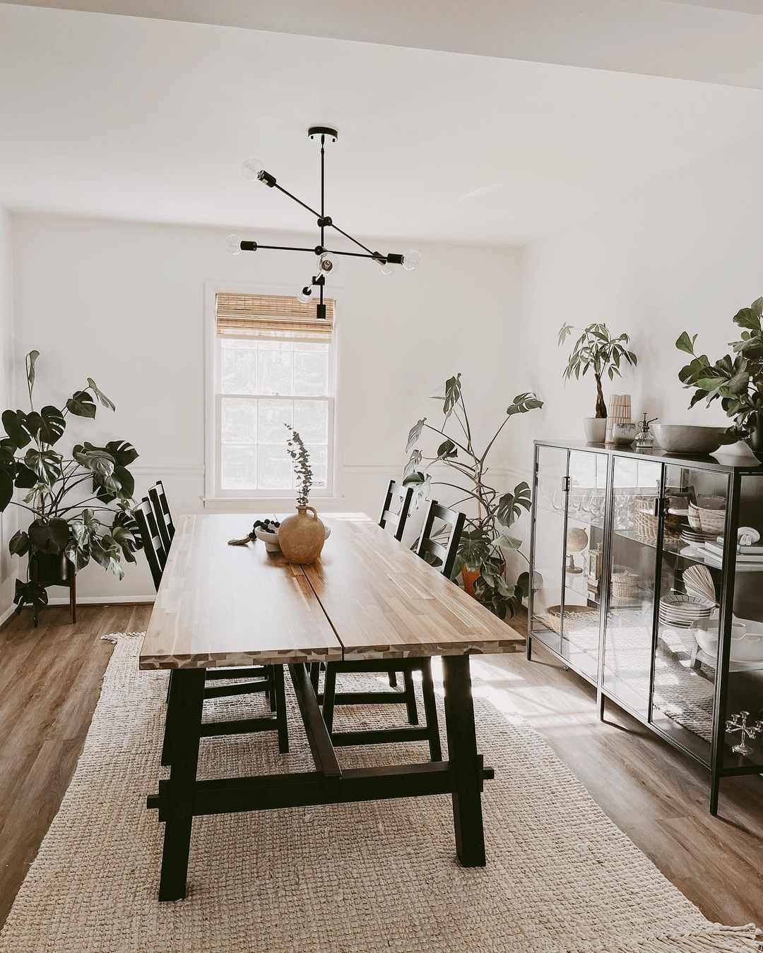 Modernes Esszimmer mit modernistischem schwarzem Kronleuchter, Kuriositätenkabinett und Pflanzen