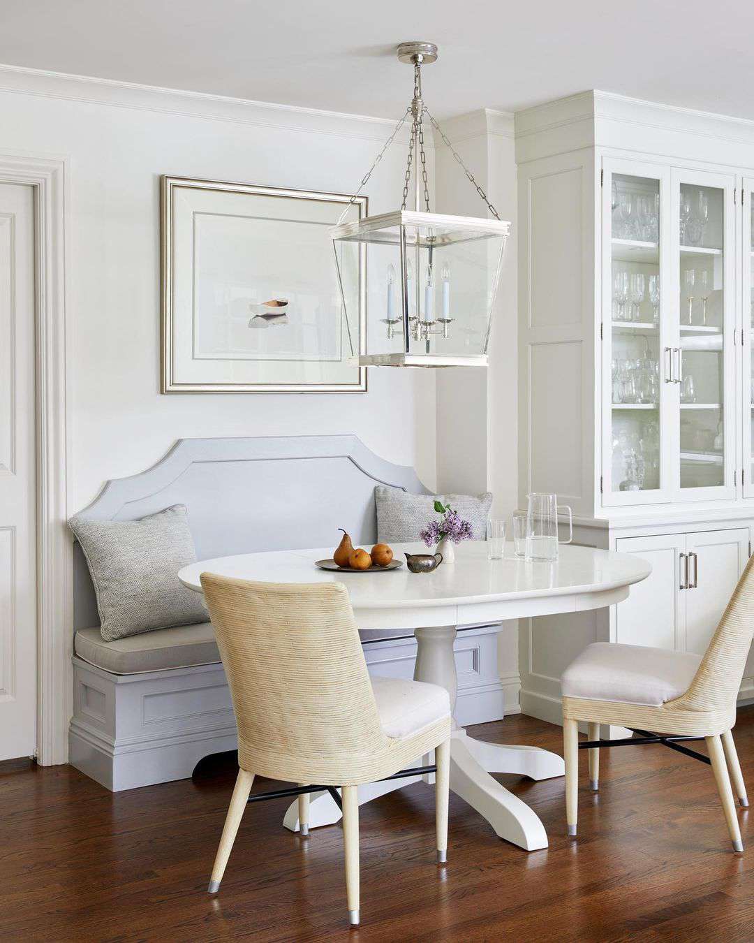 Elegantes klassisches weißes Esszimmer mit eingebautem Holzbankett, weißem Holzsockel-Esstisch und gelben, strukturierten Pantoffelstühlen