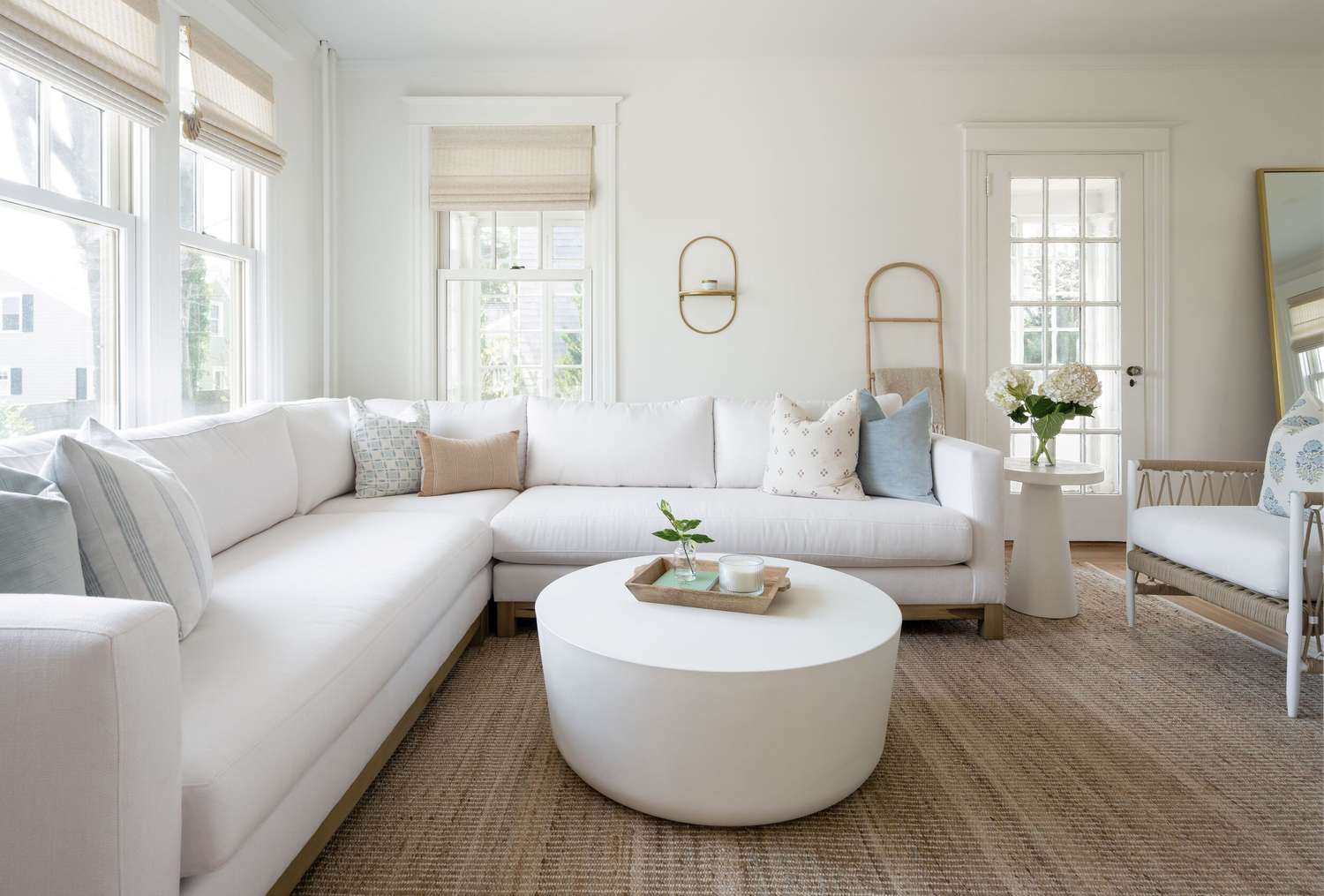 Die klassischen New England Color Combo -Designer werden diesen Sommer überall überall sein 2 Ein weiches Küsten Wohnzimmer mit einem weißen Sofa, hellblau und Jute-Akzente und einer breiten, warmen bemalten Wand