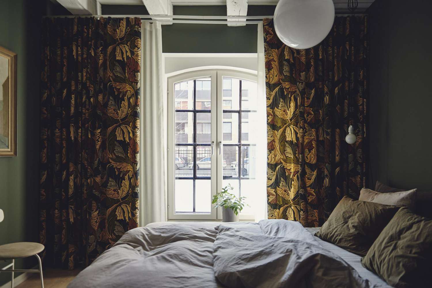 dunkelgrünes Schlafzimmer mit dunklen Blumenvorhängen