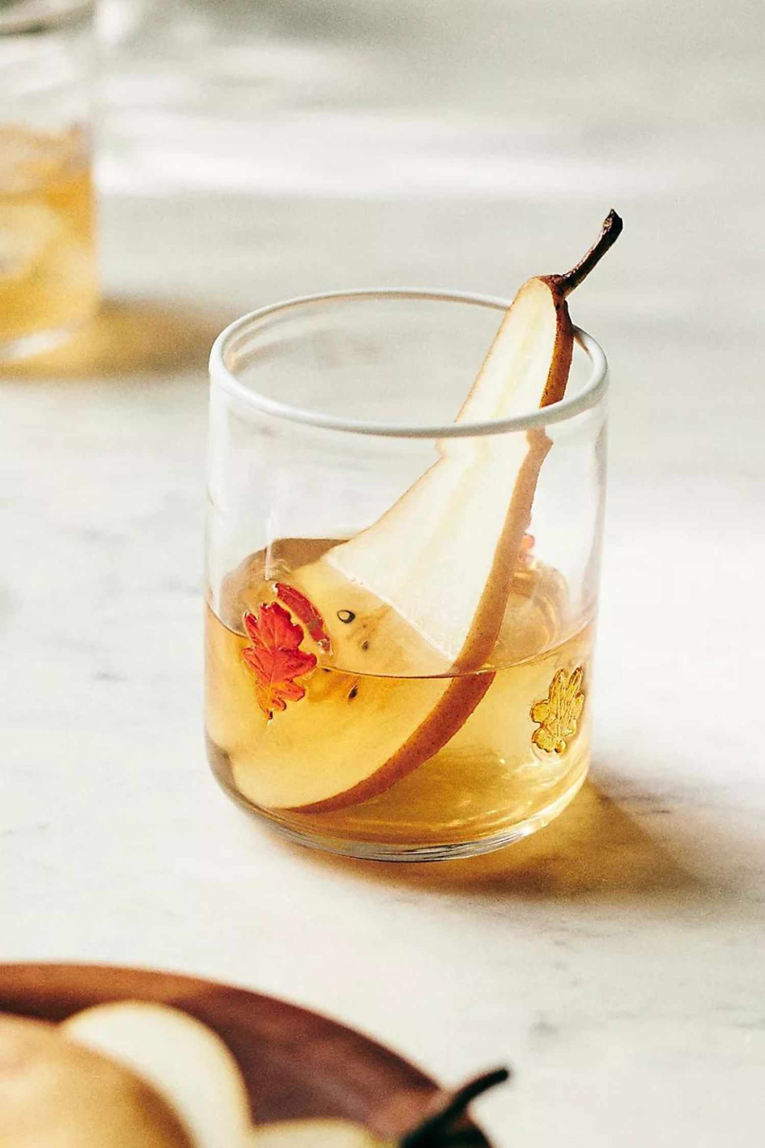 14 Herbstdekorationen von Anthropologie, die Sie nicht verpassen sollten, alle unter 20 $ 2 Ein Saftglas mit 3D-Blattmotiven, in dem sich eine Birnenscheibe und ein Getränk befinden