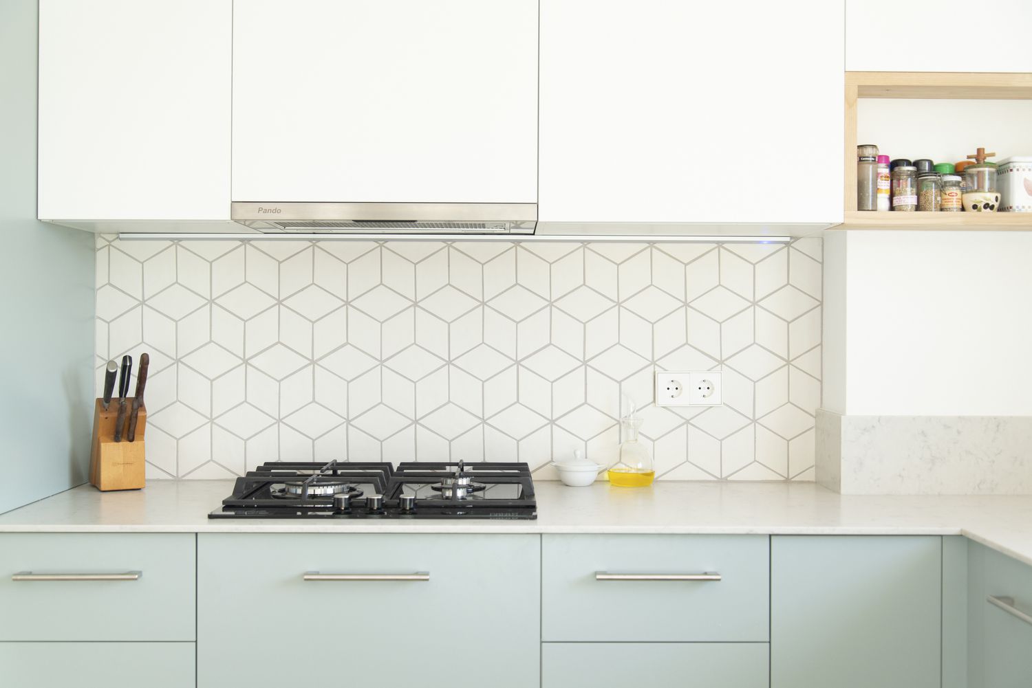 7 Küchenschrankfarben, die laut Innenarchitekten so veraltet sind 4 Kleine Küche mit weißen Oberschränken und mintgrünen Unterschränken sowie geometrischer Rückwand.