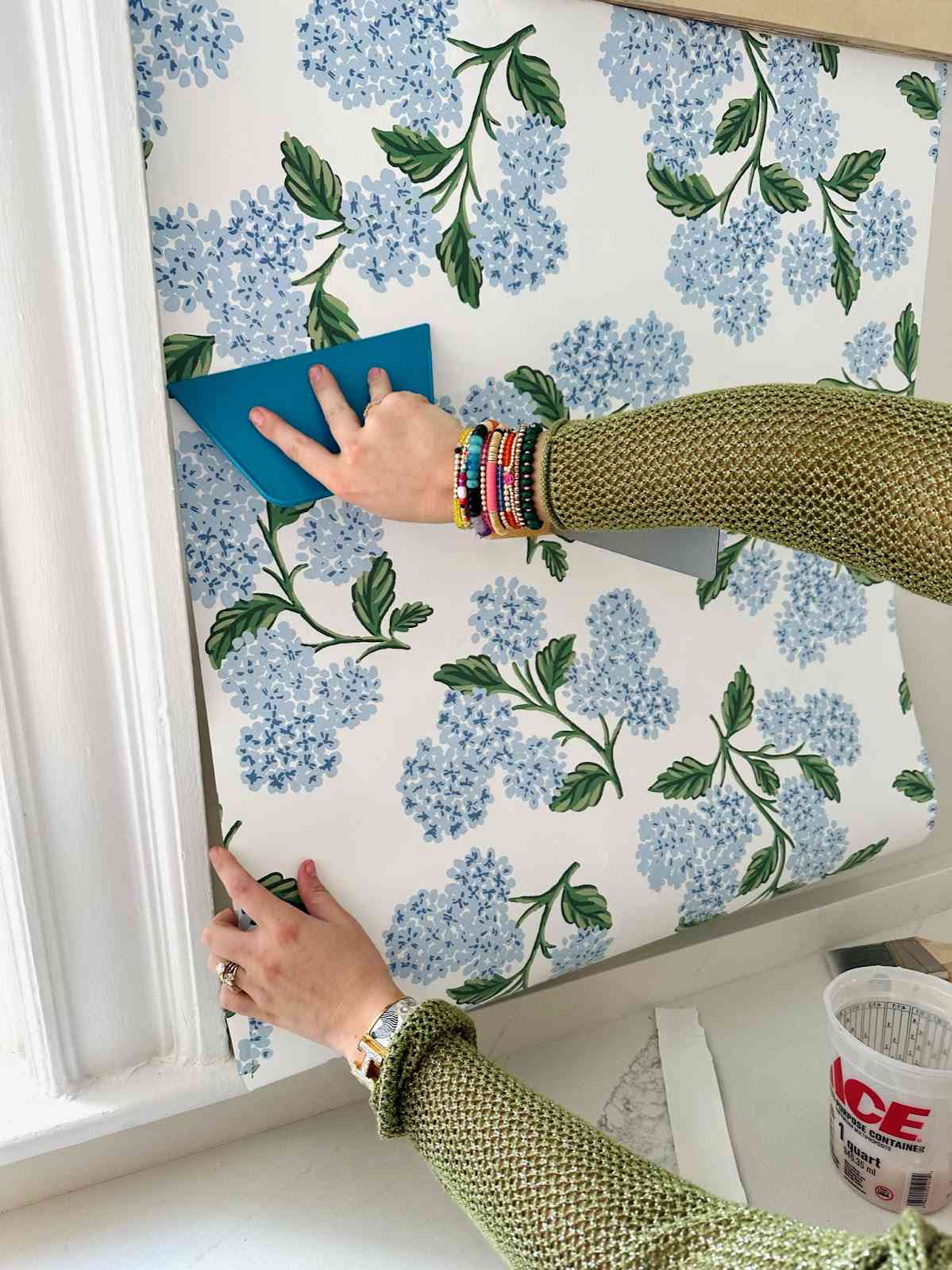 Clare glättet Tapete an der Wand.