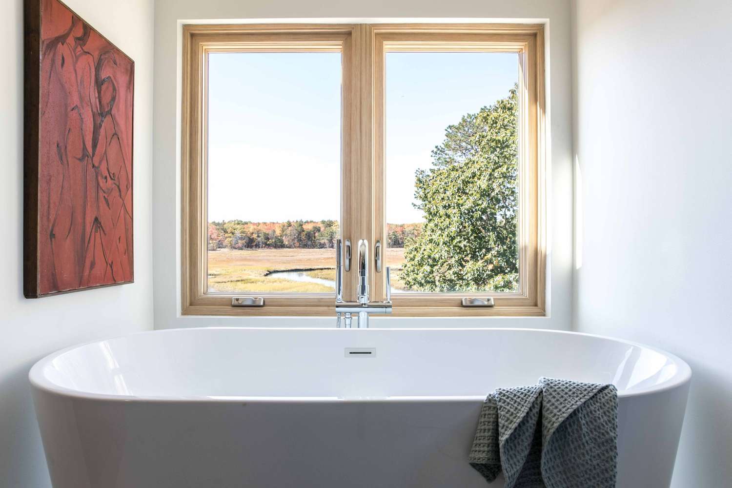 Ein kleines Badezimmer mit einer grauen freistehenden Badewanne und einem großen roten Gemälde an der Wand