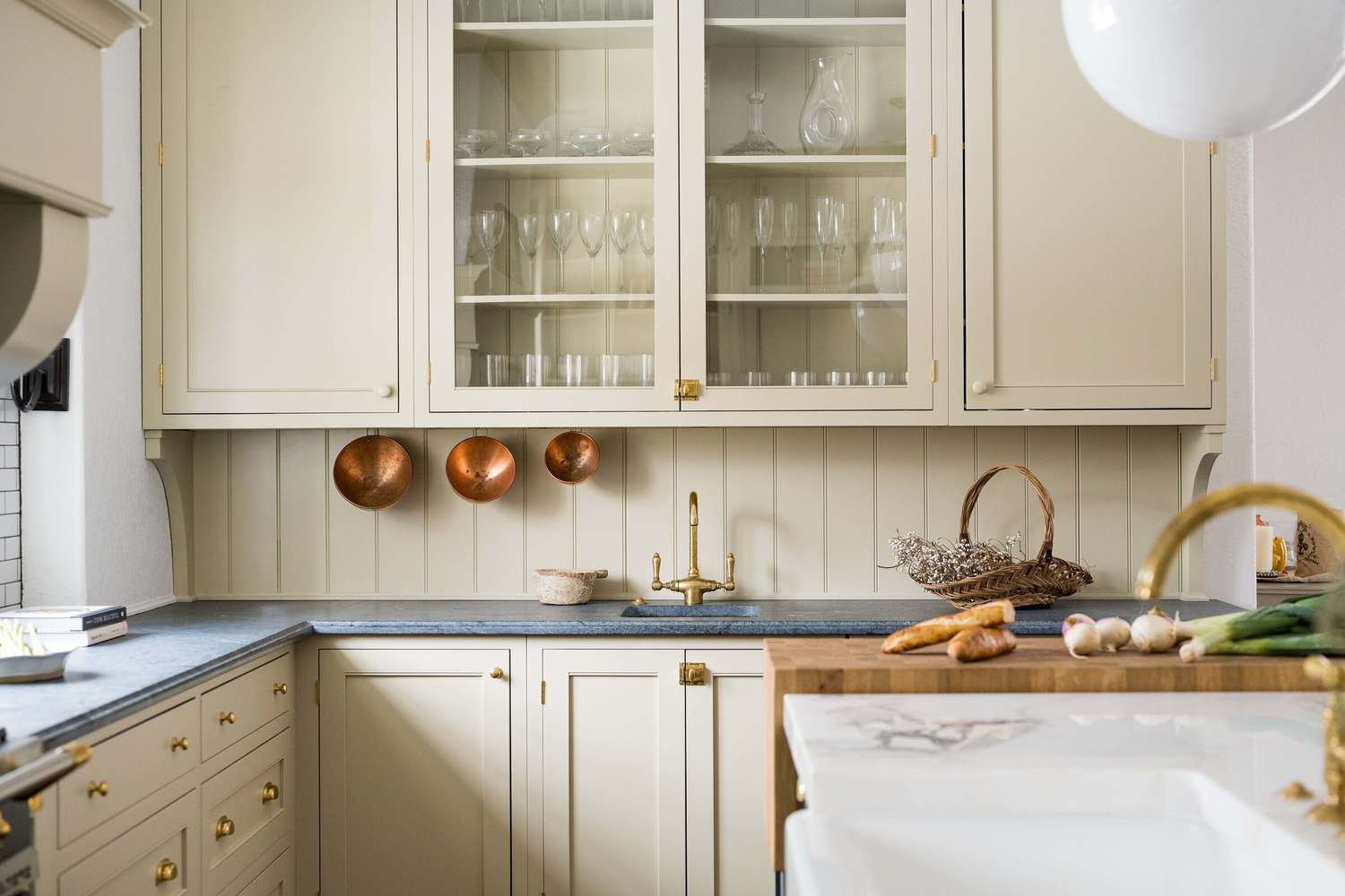Küche im Cottage-Stil mit cremefarbenen Schränken, schwarzen Arbeitsplatten und Messingbeschlägen
