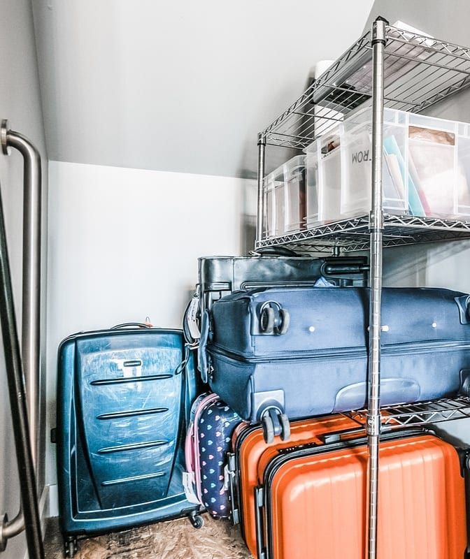 Kleiner Schrank mit schrägen Wänden und einem Metallregal voller Koffer