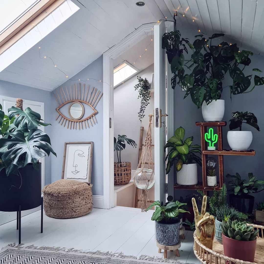 Zimmer mit schräger Decke und vielen Pflanzen darin