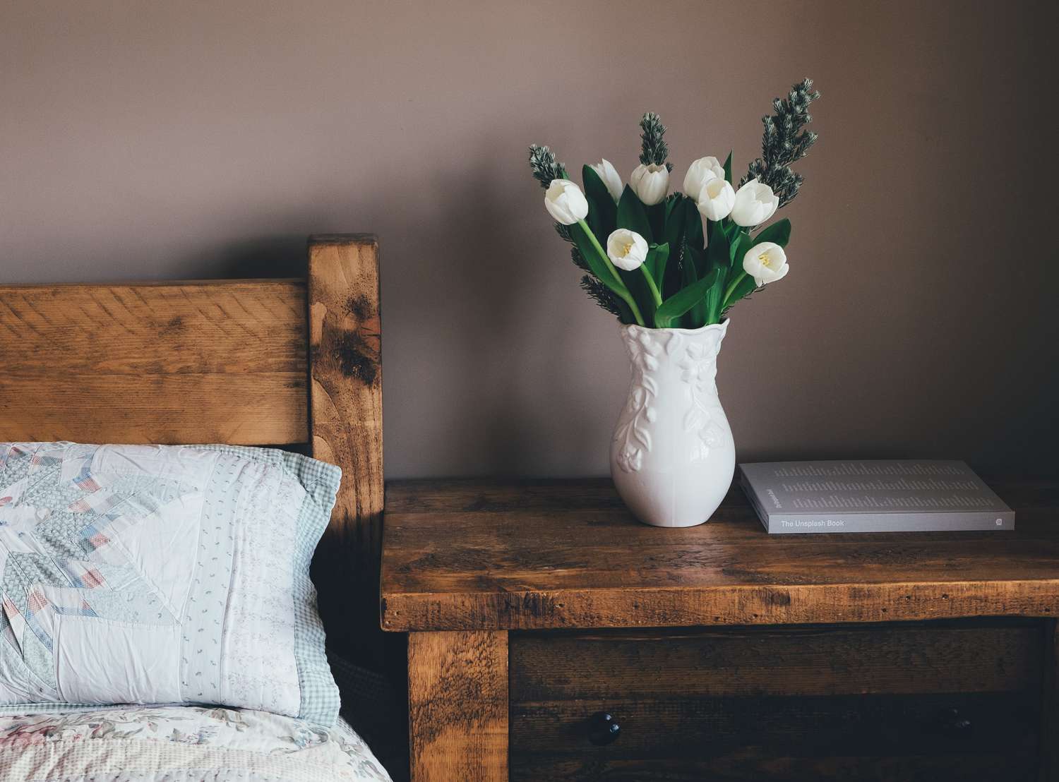 Schlafzimmer mit Holzmöbeln und frischen weißen Tulpen in einer Vase