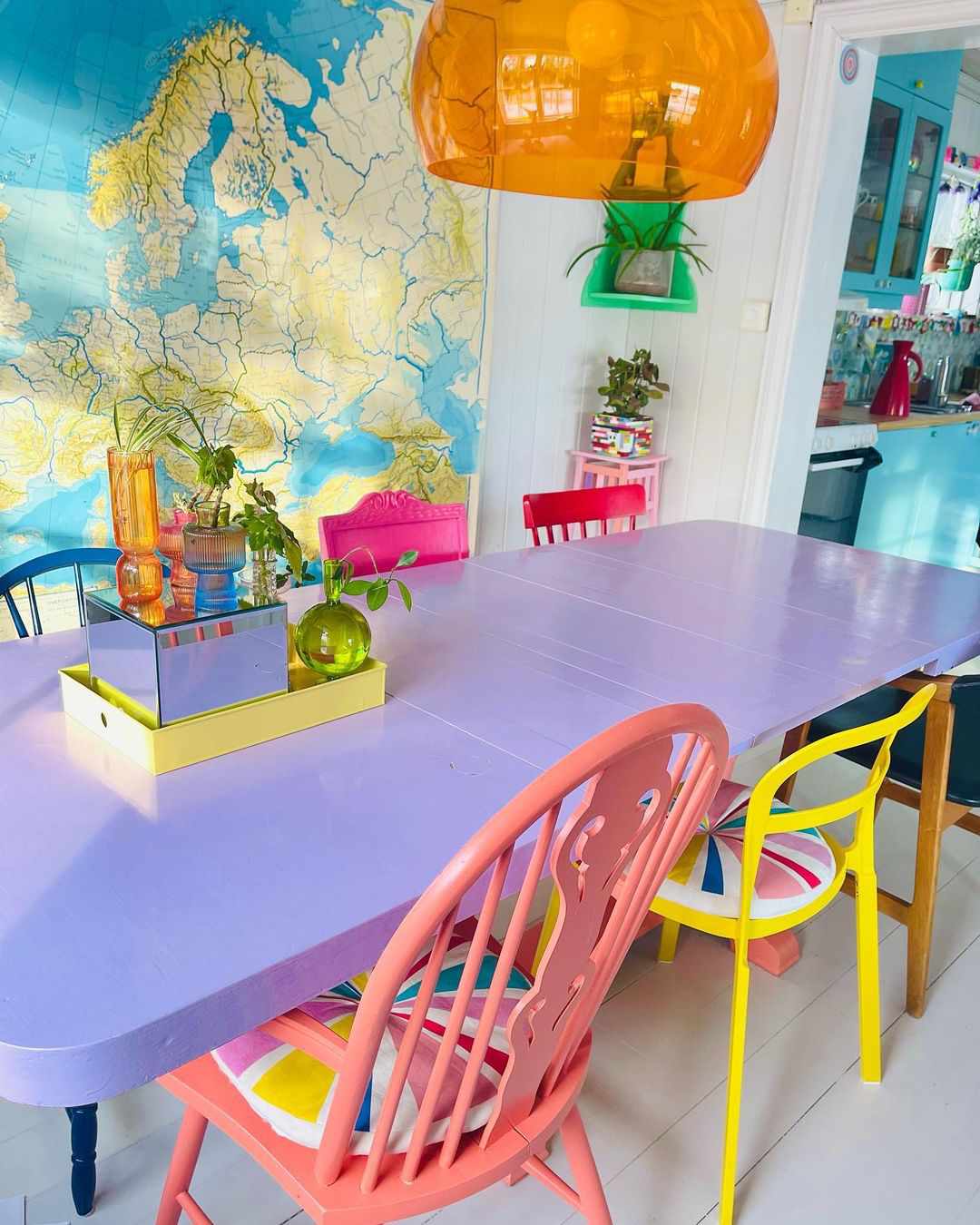 Lila Tisch und bunte Stühle