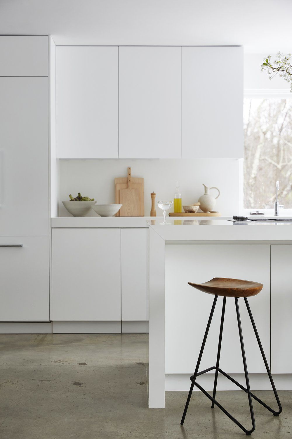 Moderne Küche mit weißen Schränken und Kücheninsel sowie einem hölzernen Barhocker
