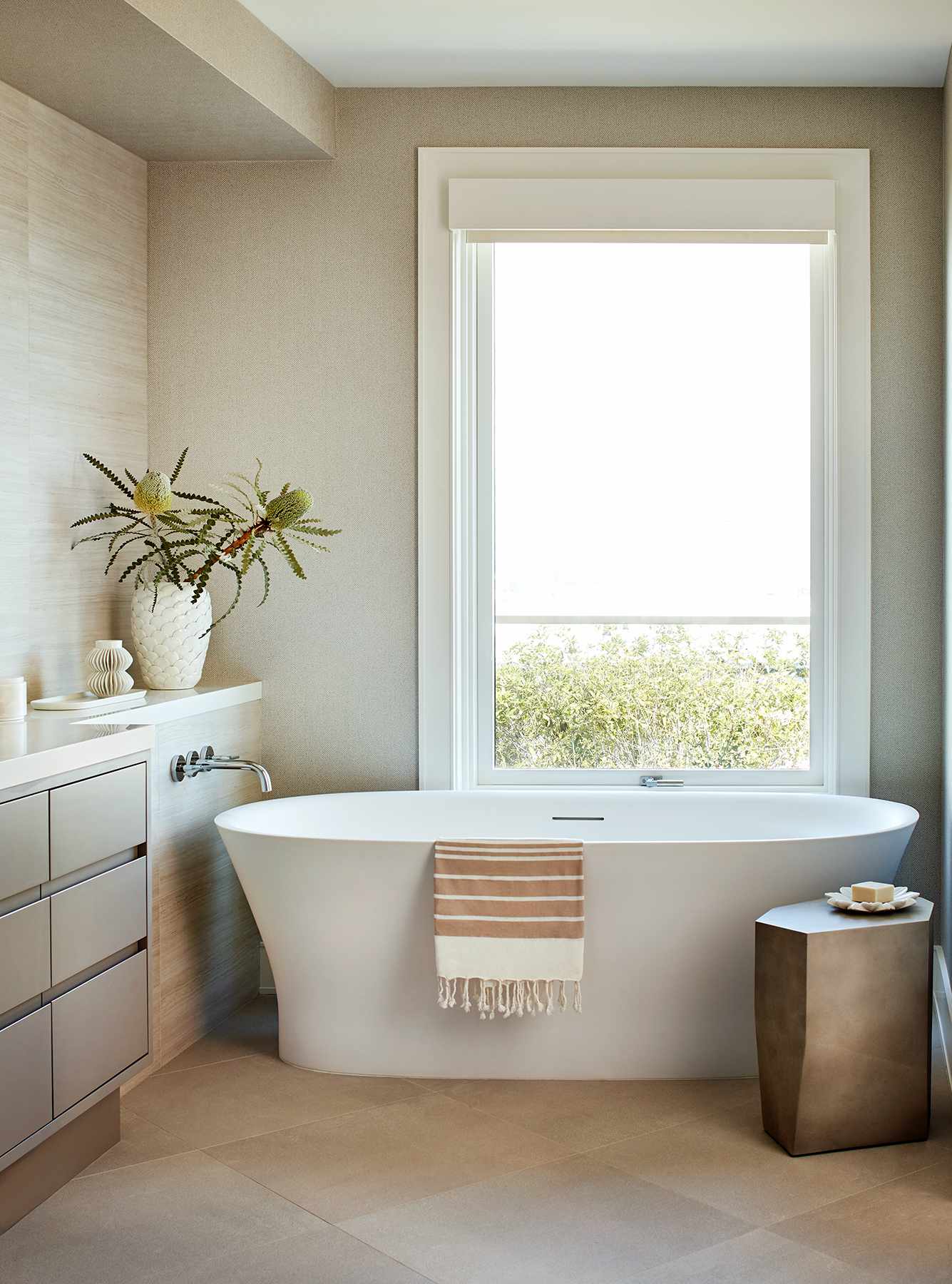 In einem Badezimmer mit beige gestrichenen Wänden steht eine große Badewanne