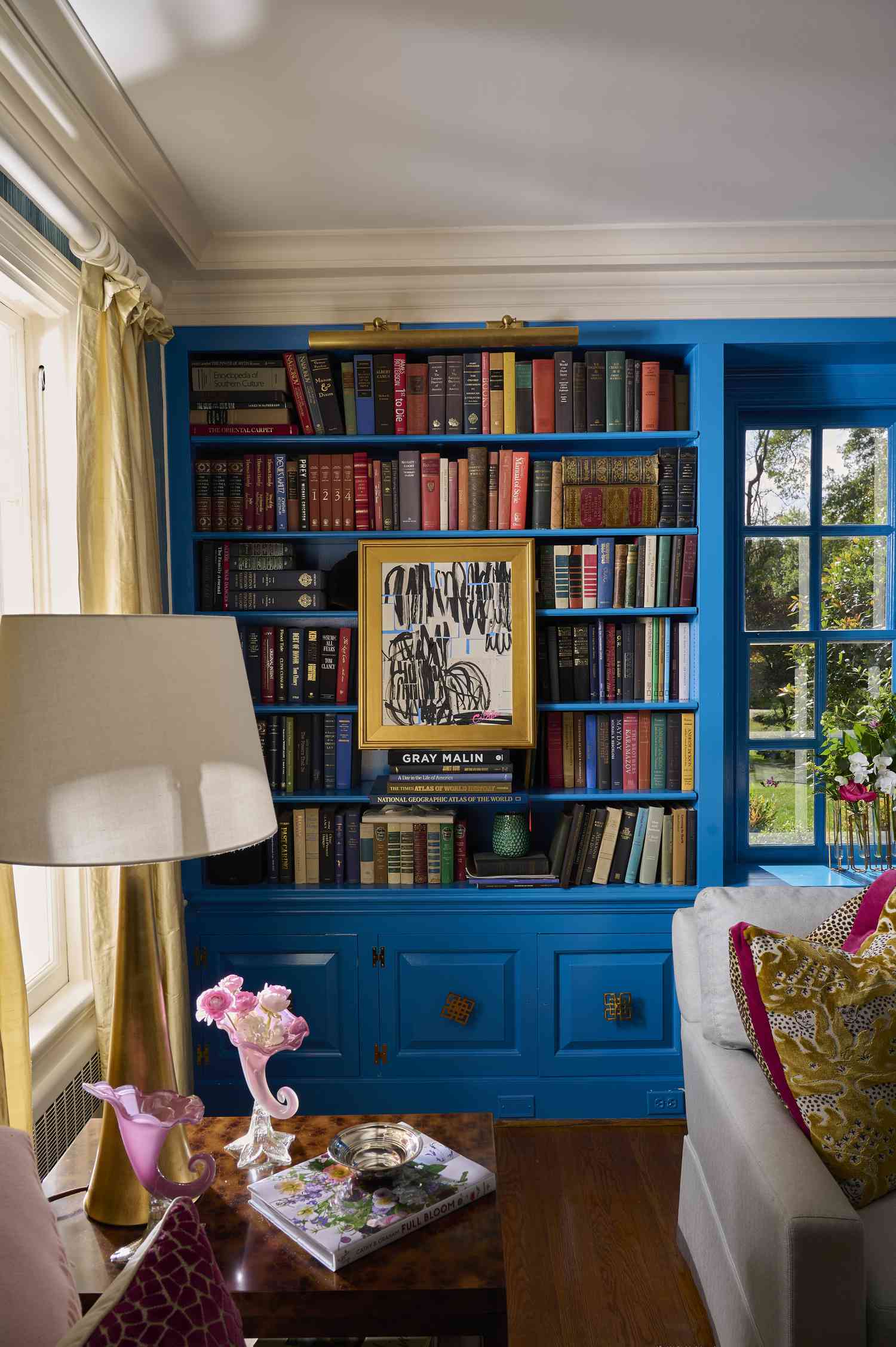 Minimalismus ist offiziell out – Warum Designer diesen Herbst einen neuen, farbenfrohen Stil lieben 4 Zimmer mit leuchtend blauem Bücherregal sowie farbenfrohen Kunstwerken und Kissen