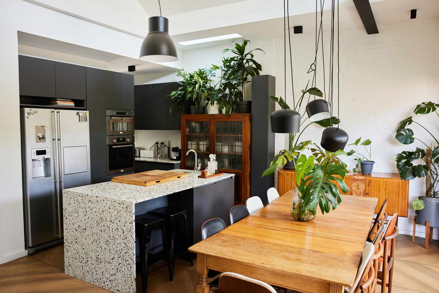 5 Farben, die Sie in Ihrer Küche niemals verwenden sollten, warnen Designer 8 Stühle sitzen um einen großen Tisch in einem offenen Haus mit einer modernen Küche im Hintergrund