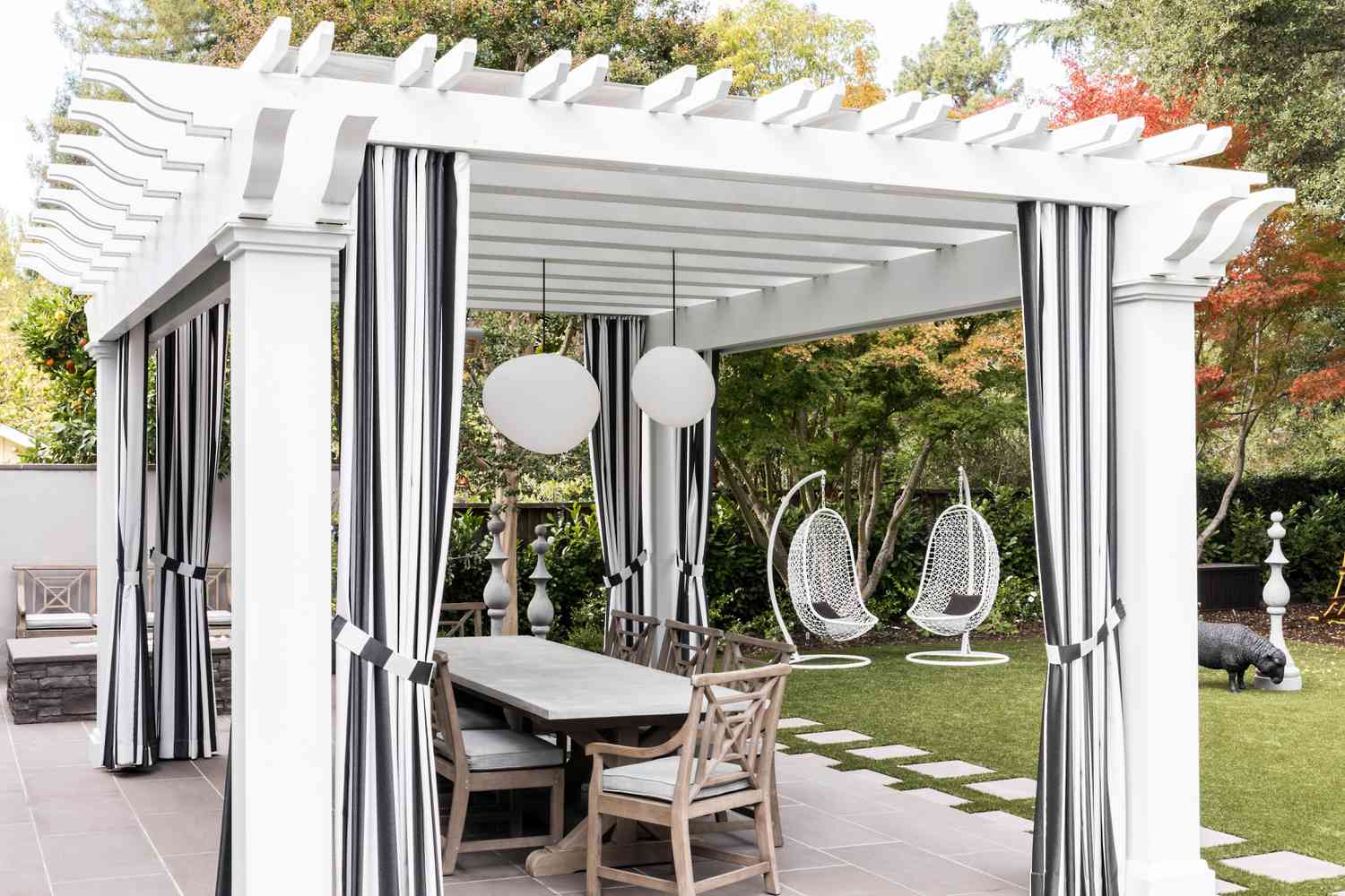 weiße Pergola, drapiert mit schwarz-weiß gestreiften Cabana-Vorhängen