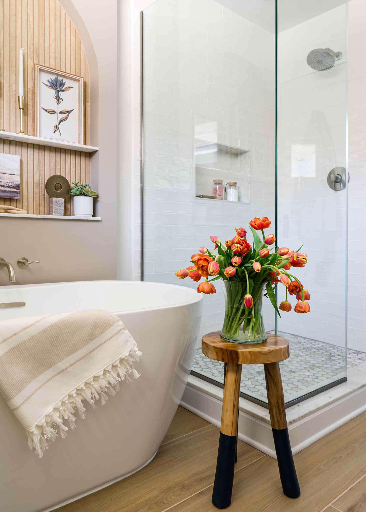 Der Holzboden beherbergt eine glatte weiße Badewanne mit einer Glasdusche in der Nähe