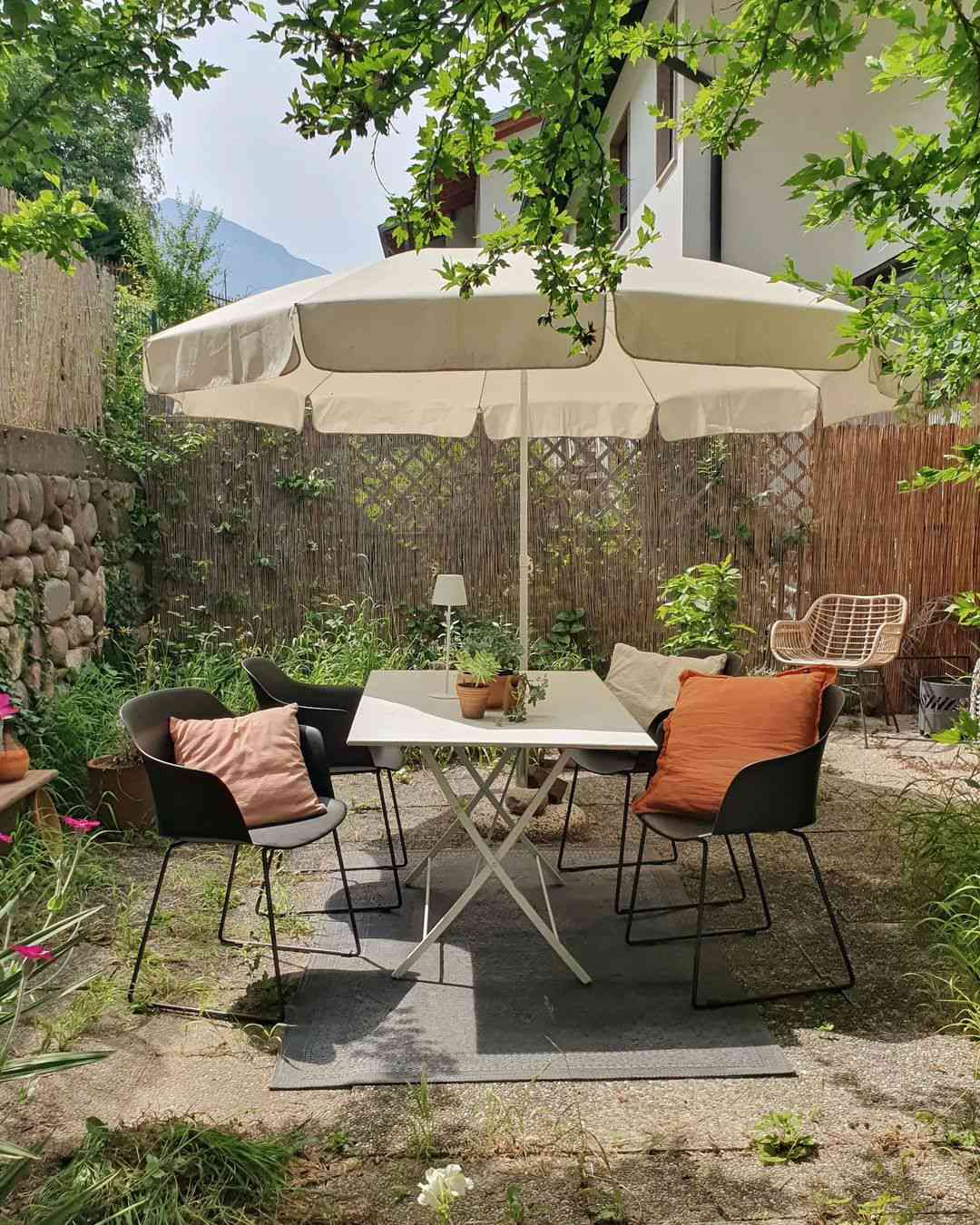 kleine Terrasse mit Sonnenschirm und bunten Kissen
