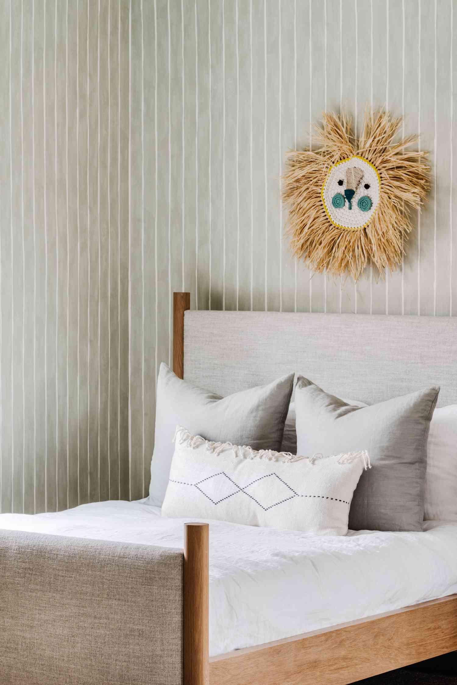 graues Bett und gestreifte Tapete