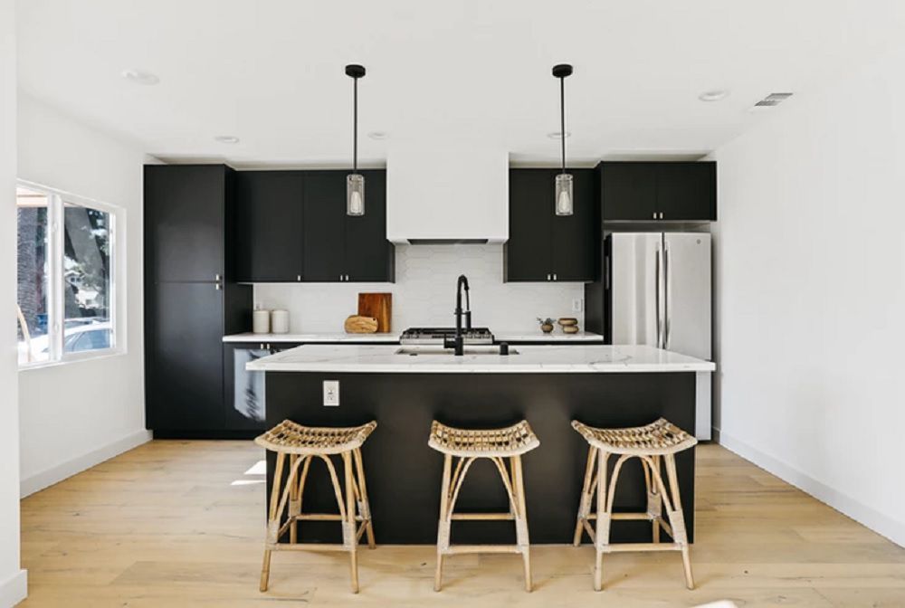 A kitchen with a black island and cabinetry