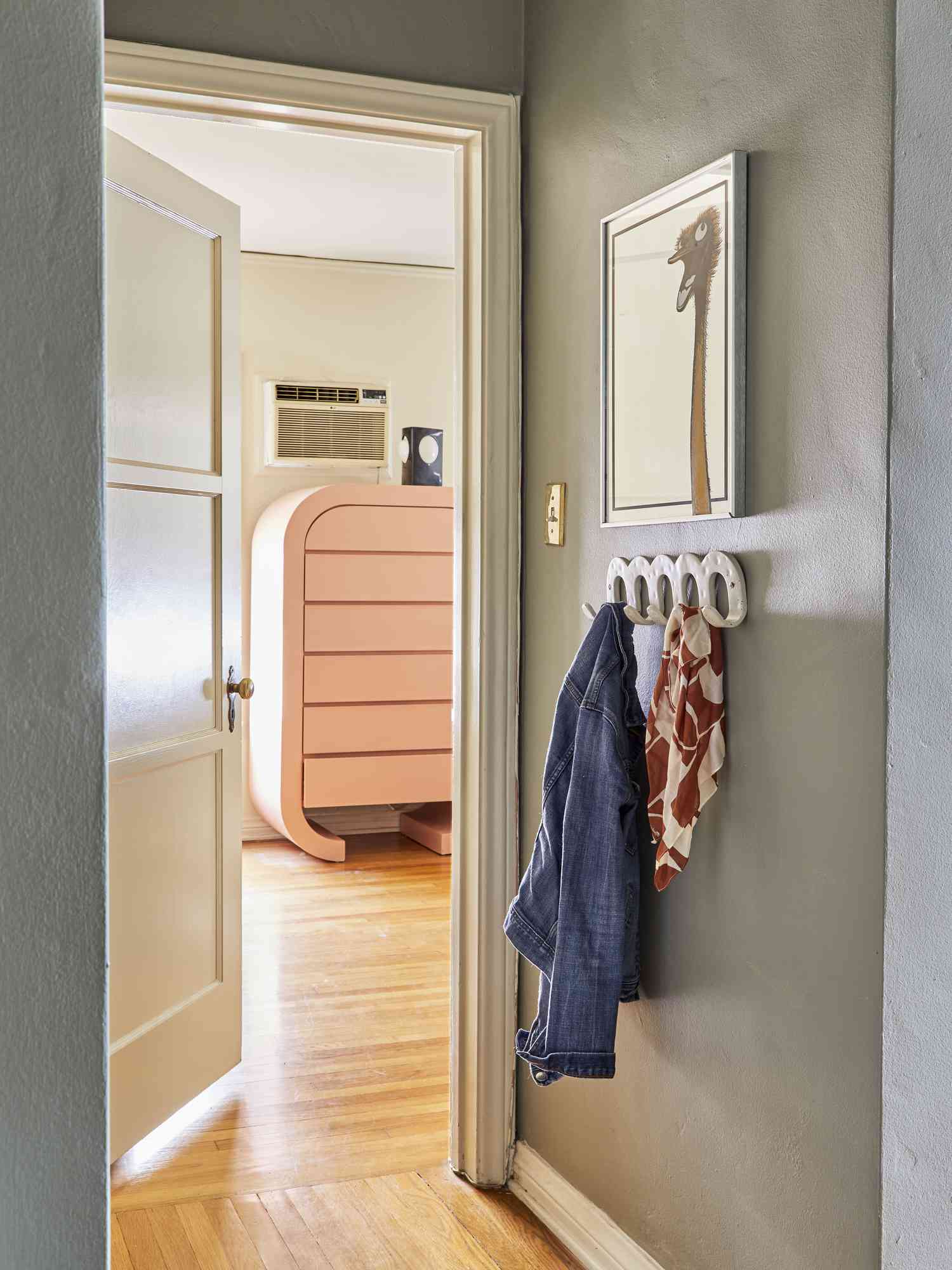Wall-mounted coat hanger on the wall under a picture in a narrow hallway