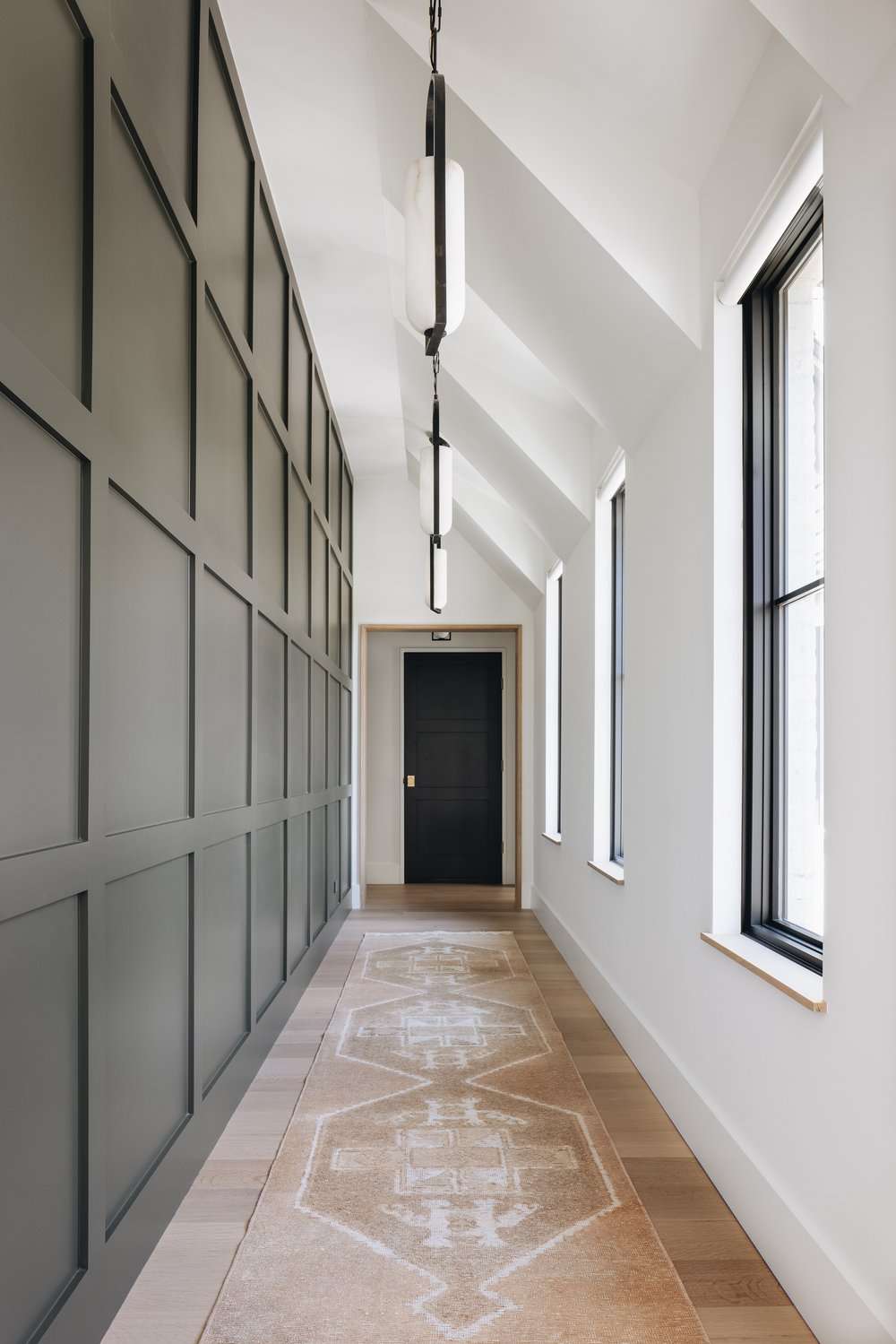Narrow hallway with sloped ceiling and dark wood paneled wall