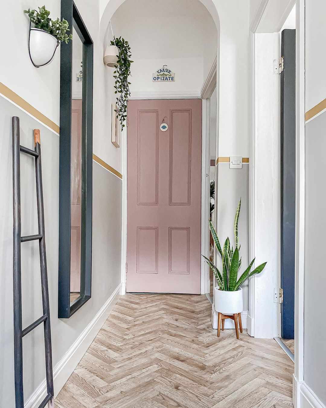Narrow hallway with plants on the wall, hanging mirror and a leaning ladder