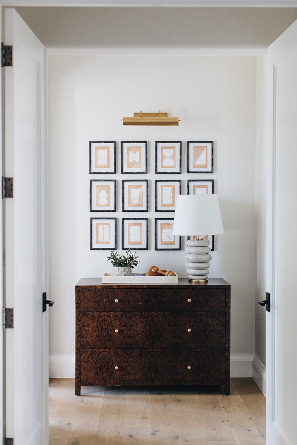 Narrow hallway with a cabinet and gallery wall above it
