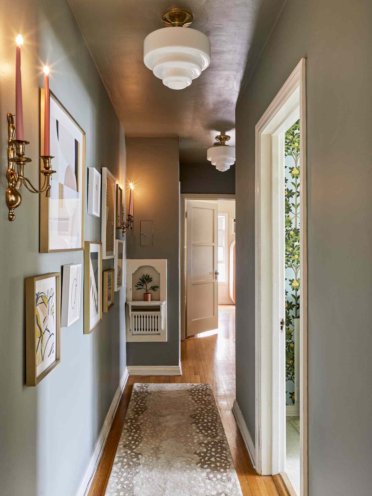 Narrow hallway with artwork and candelabra on the wall