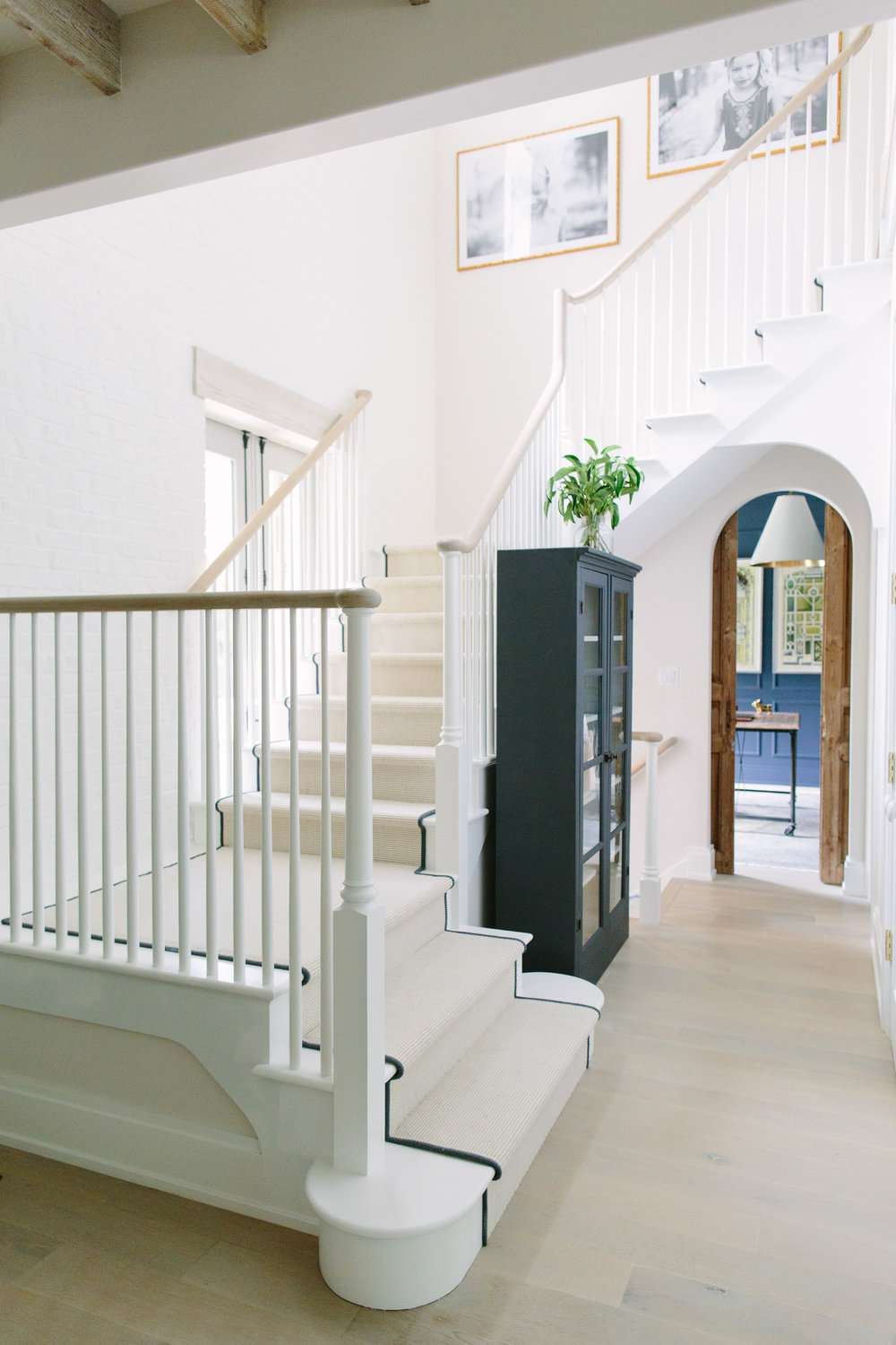 Tall black cabinet in a narrow hallway by a staircase