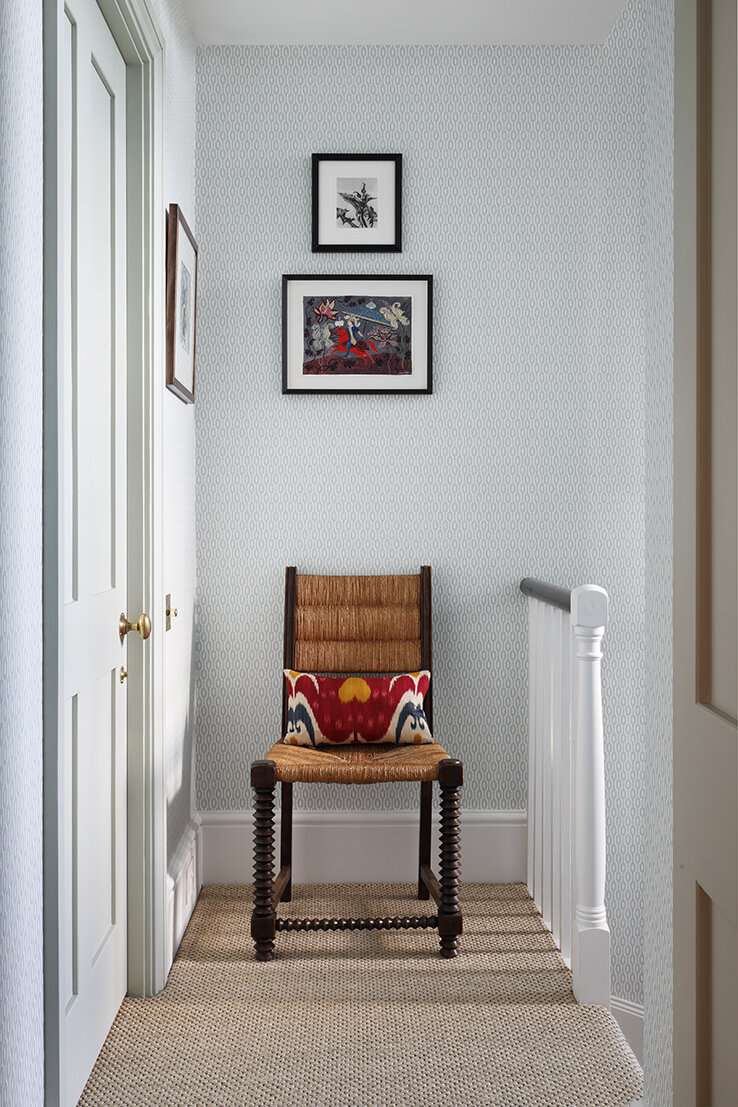 A chair at the end of a narrow hallway with artwork above it