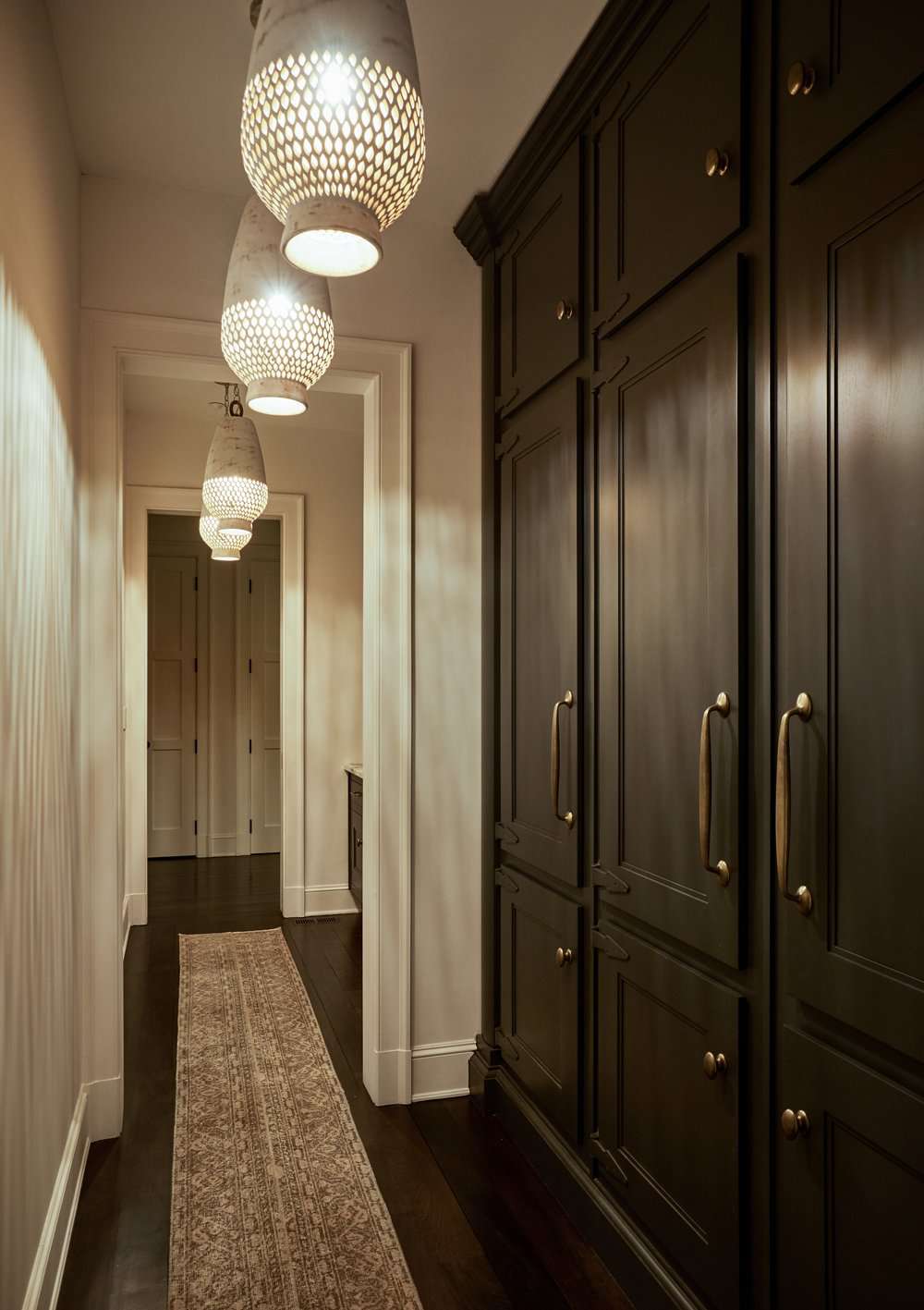 Wall of black floor to ceiling built-in cabinets in a narrow hallway