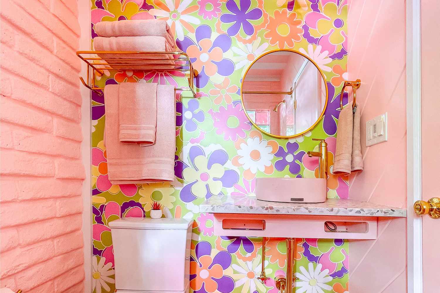 Pink statement bathroom with bold colorful daisy print wallpaper