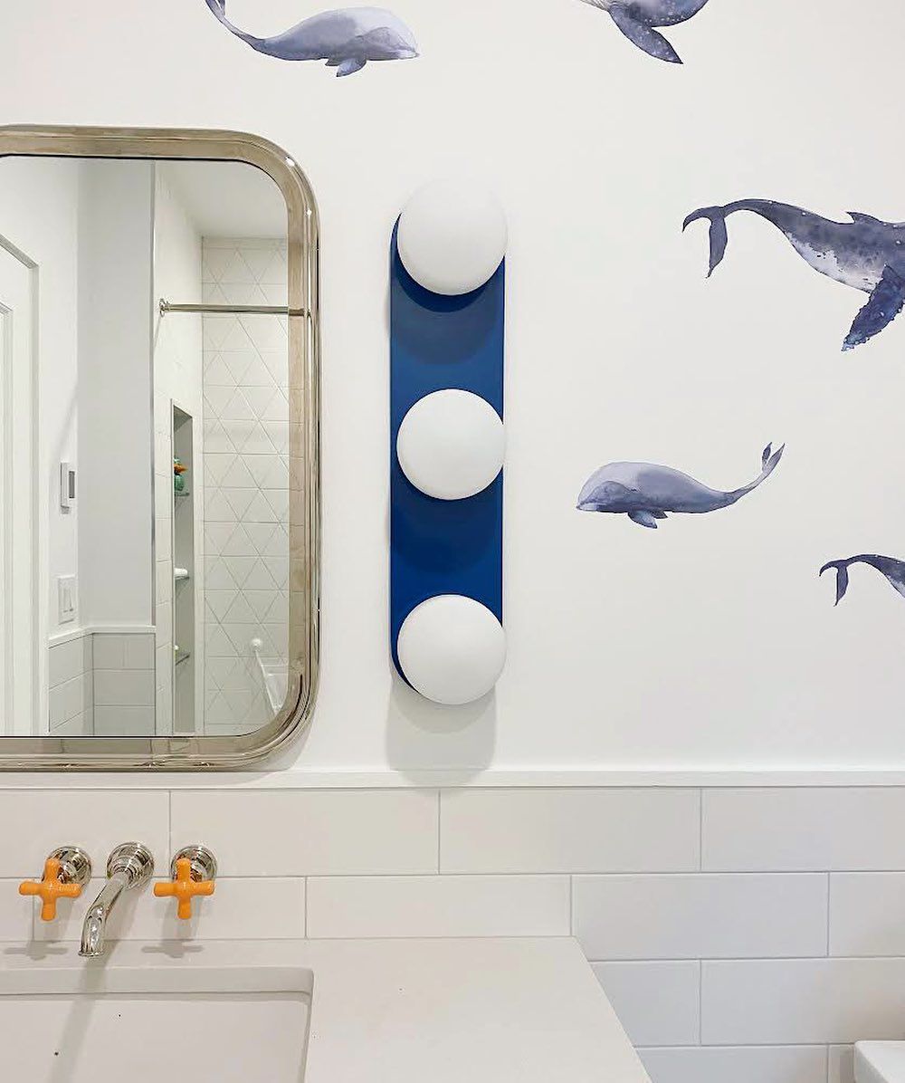 Whale wallpaper and blue light fixture in bathroom