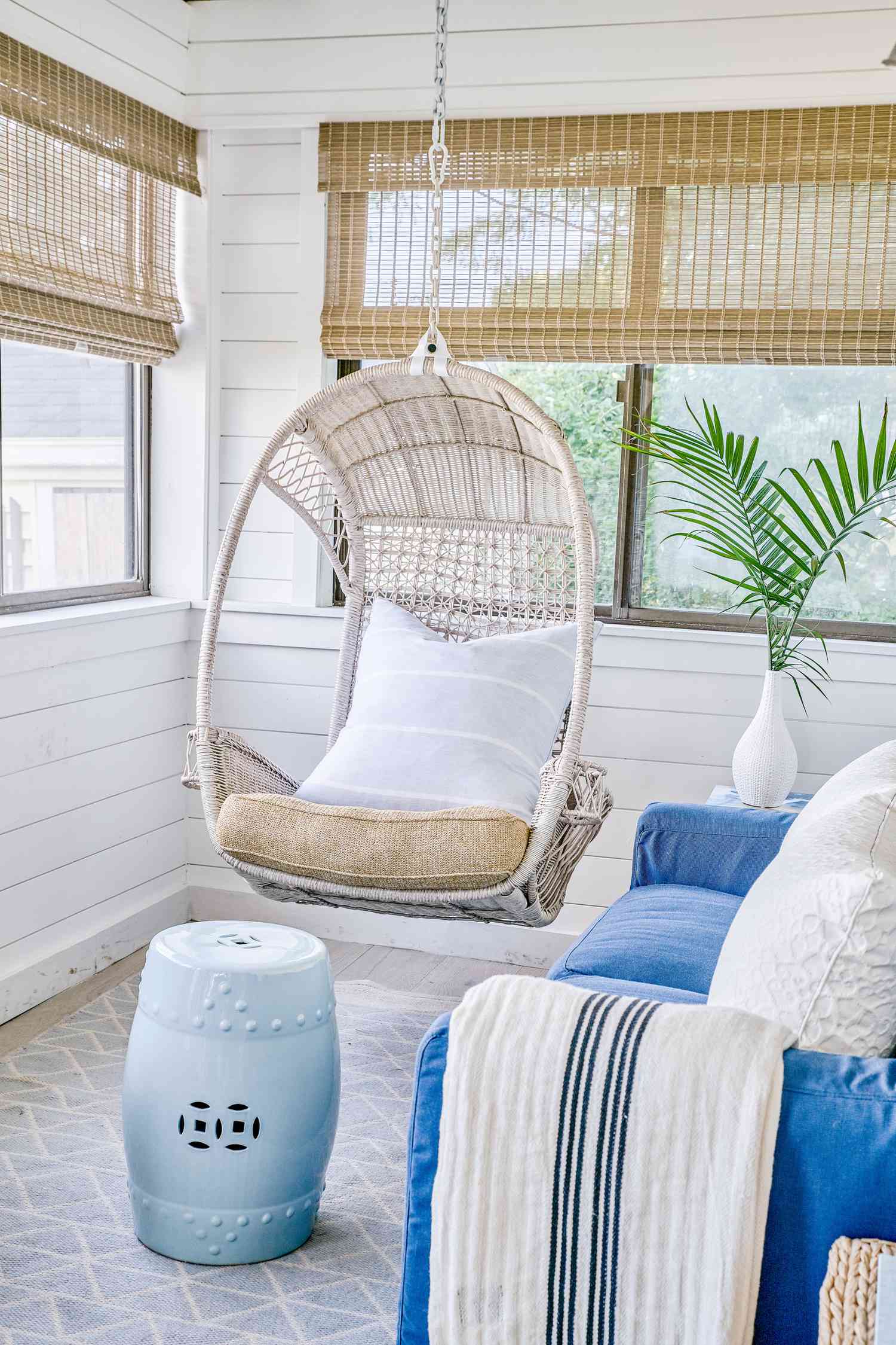48 Small Sunroom Ideas for a Warm and Happy Space 12 Hanging rattan chair in a white sunroom with woven wood blinds