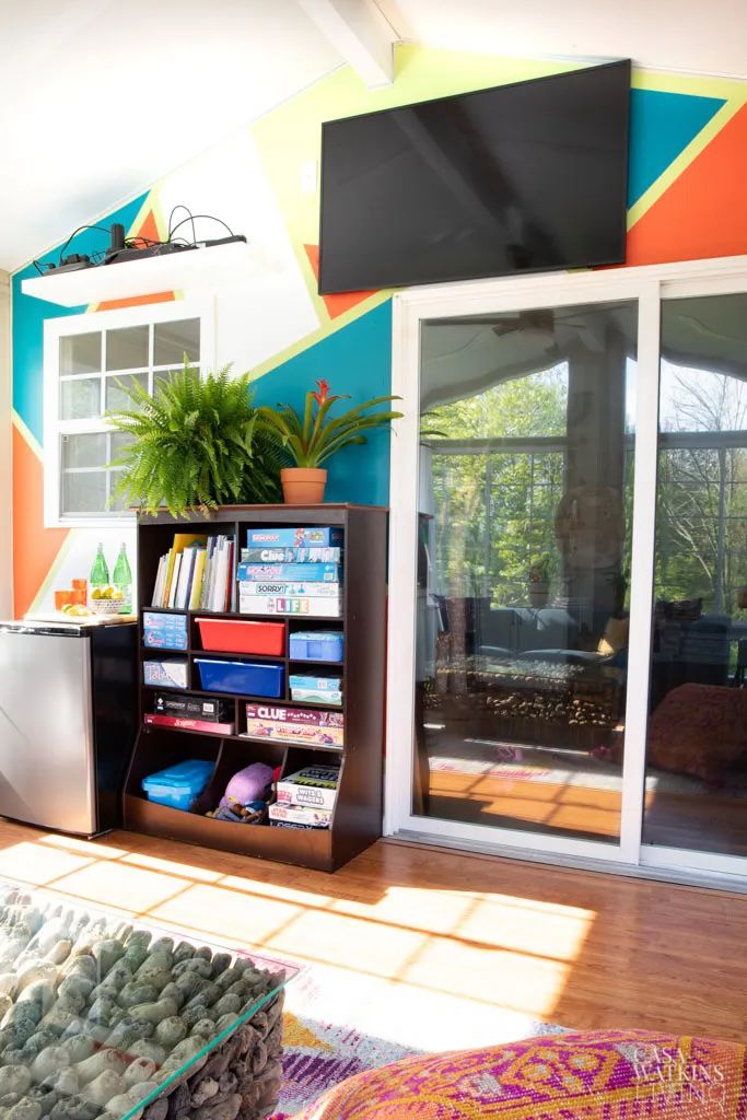 48 Small Sunroom Ideas for a Warm and Happy Space 22 Color blocked sunroom wall and a TV mounted on the wall and a bookshelf with board games underneath it