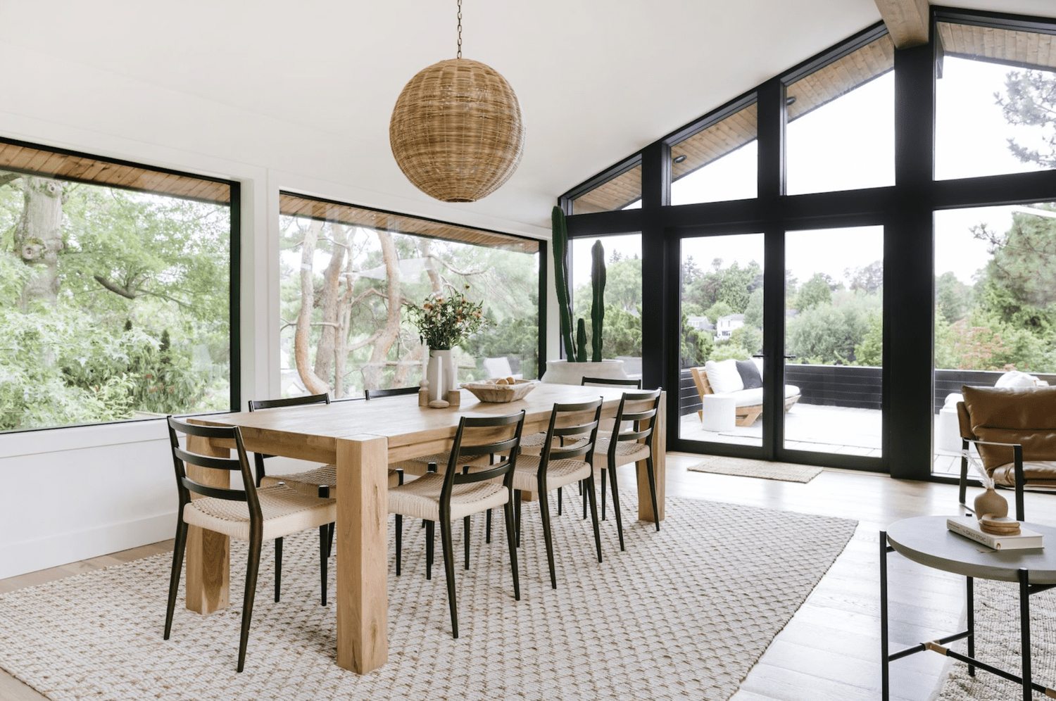 48 Small Sunroom Ideas for a Warm and Happy Space 46 Sunroom with white walls, black window frames, wood furniture and rattan pendant light