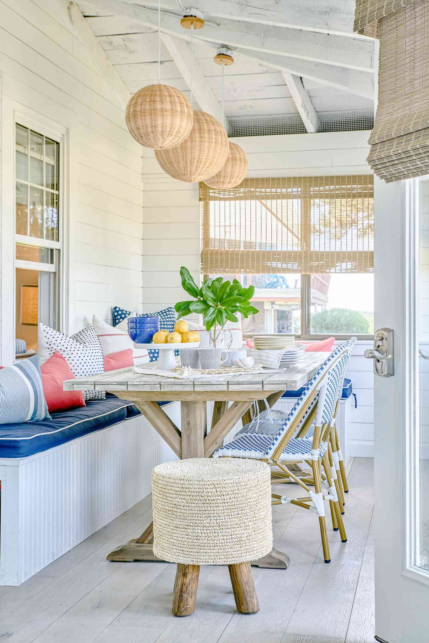 48 Small Sunroom Ideas for a Warm and Happy Space 26 Small sunroom with a built-in dining bench around a wood table with blue and white chairs and rattan pendant lights hanging from the ceiling