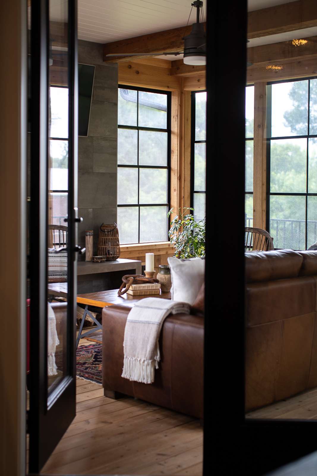 48 Small Sunroom Ideas for a Warm and Happy Space 16 Modern rustic sunroom with wood walls, stone fireplace, and leather furniture
