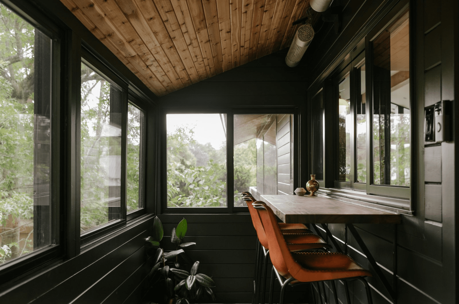 48 Small Sunroom Ideas for a Warm and Happy Space 24 Small sunroom with black walls, wood ceiling and built-in counter with leather bar stools