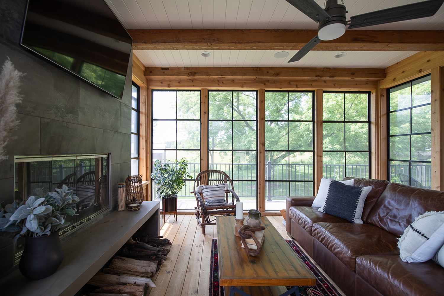 48 Small Sunroom Ideas for a Warm and Happy Space 68 Sunroom with wood walls and flooring and a stone fireplace with a TV mounted above it