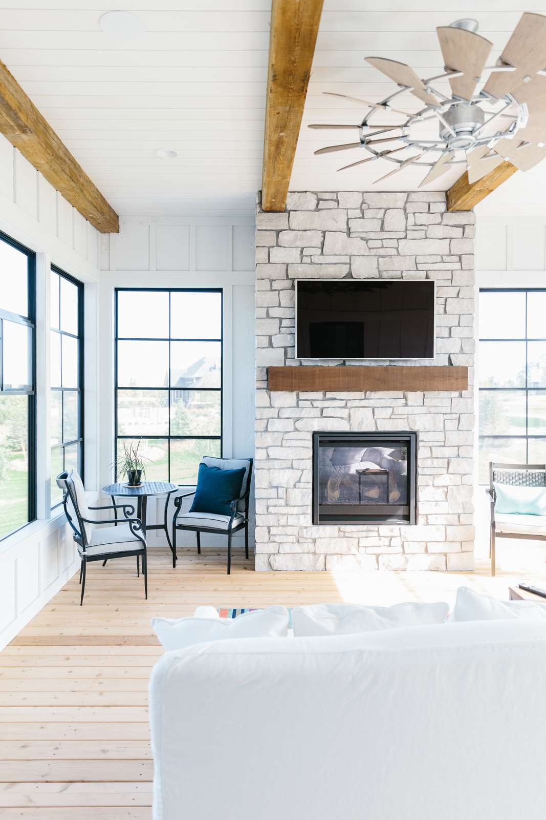 48 Small Sunroom Ideas for a Warm and Happy Space 74 Sunroom with wood ceiling beams and a stone fireplace accent wall with a TV mounted above the mantel