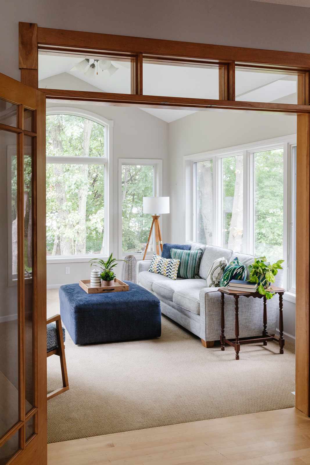 48 Small Sunroom Ideas for a Warm and Happy Space 90 Light gray walls in a sunroom with large windows, gray sofa and blue ottoman coffee table