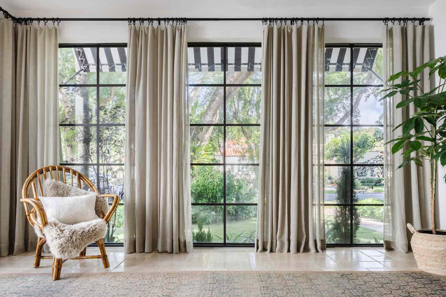 48 Small Sunroom Ideas for a Warm and Happy Space 88 Floor-to-ceiling curtain panels from wall to wall in a sunroom with tiled floors and a rattan armchair in the corner