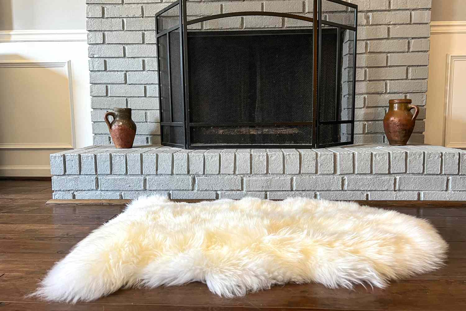 Der Quitten australische Single -Schaffell -Teppich auf einem Holzboden in der Nähe des Kamins