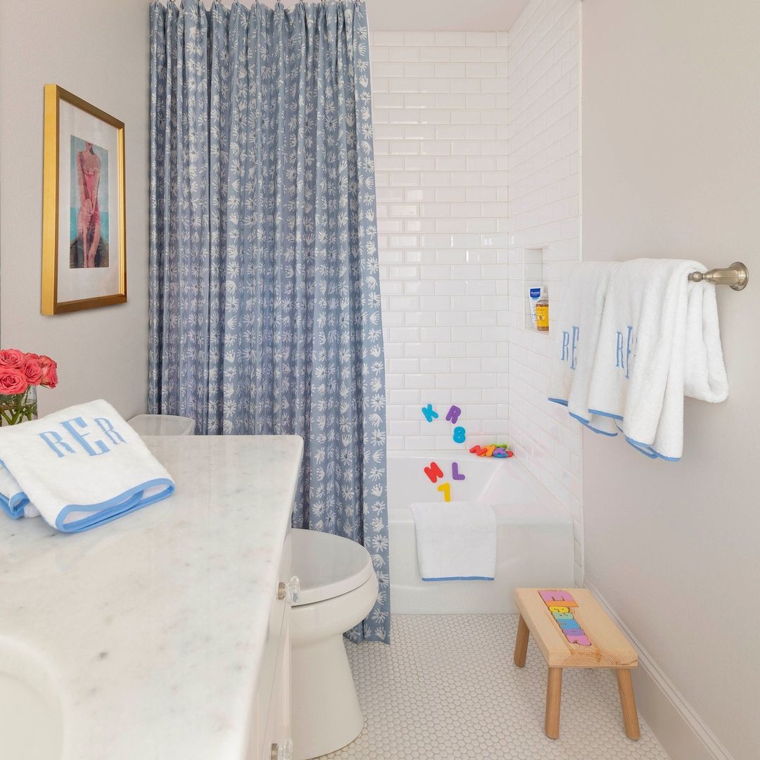 Bathroom with blue patterned shower curtain and alphabet letters on tile
