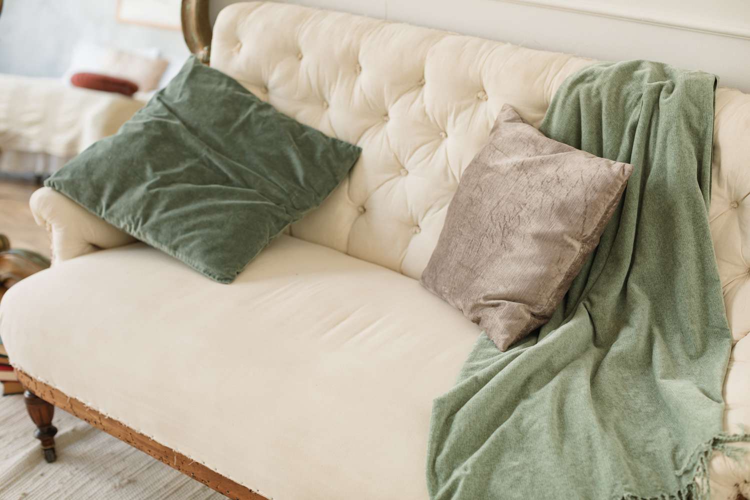 6 Couch -Stile, die laut Designer so veraltet sind 8 Weißes getuftetes Sofa mit grünen und grauen Kissen und Decke
